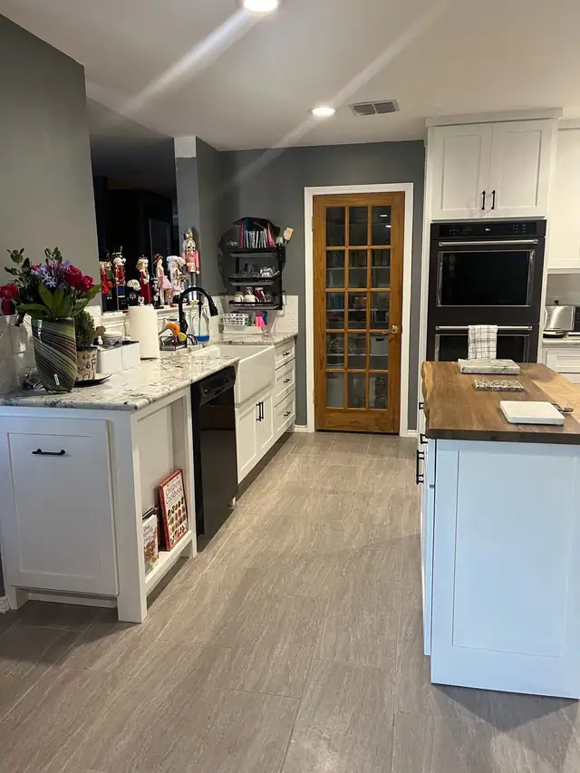 White kitchen cabinets and island with a wood glass-panel pantry door