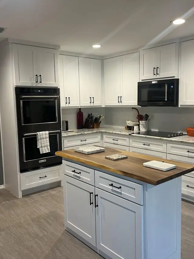 White kitchen cabinets with a butcher block island and a double wall oven