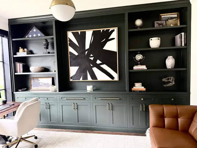 Deep green built-in cabinets with open shelves along a home office wall
