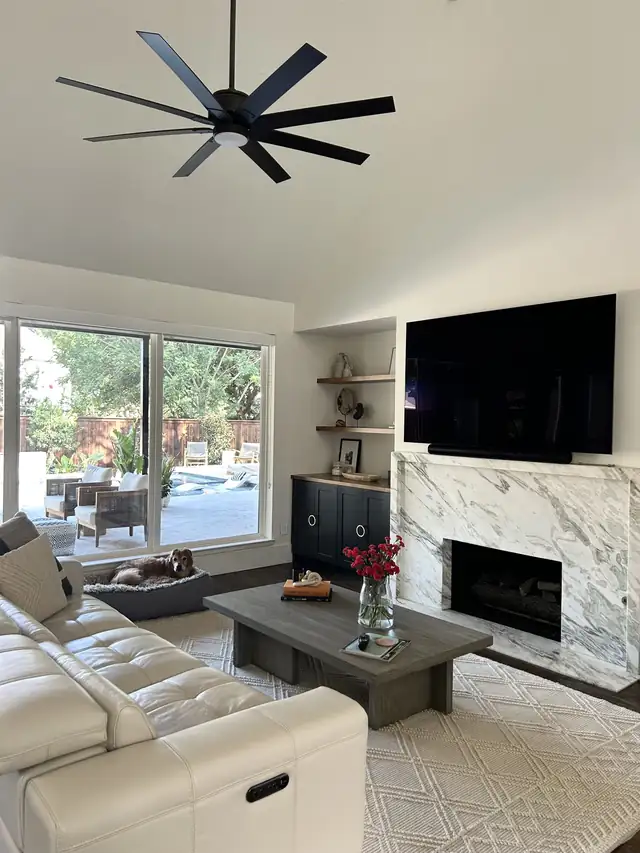 Living room with marble fireplace, cabinets and floating shelves